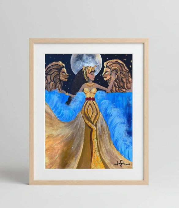 A framed art print featuring a stylized illustration of a woman in a gold dress with blue flowing forms behind her, under a full moon and starry sky. The print is set in a light wood frame with a white mat, photographed against a neutral light gray background.